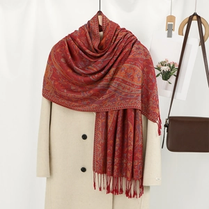 Vue détaillée d'une écharpe rouge à motifs cachemire et franges sur un manteau beige