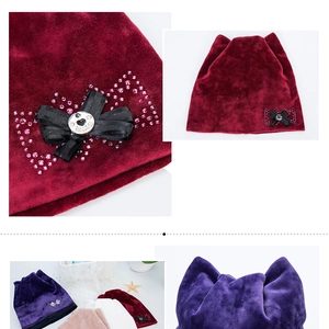 Detail of velvet beanie with cat ears featuring a black bow and heart-shaped Love charm