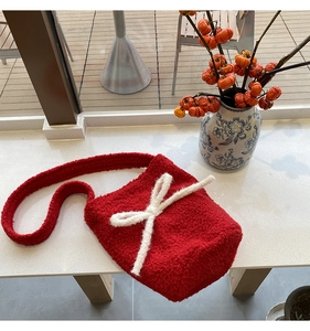 Detail showing plush red faux fur texture and a large white bow on this bucket bag