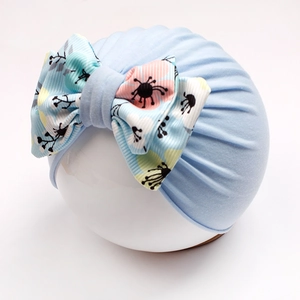 Light blue baby turban hat featuring a large floral bow on a white model head