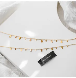 Detail of minimalist gold-plated titanium necklaces with teardrop and rectangle charms