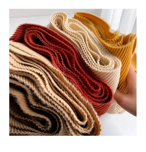 Close-up of pleated texture on thick winter scarves in brown, beige, red, and yellow