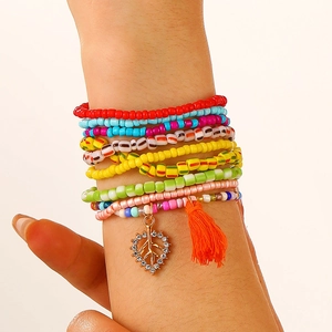 Detail of colorful multilayer beaded anklet with peace sign charm and orange tassel