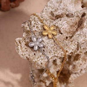 Detailed shot of gold and silver flower bracelets with beaded edges on a stone surface