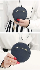 Detail showing the cat ear metal decoration and golden zipper on this navy round coin purse