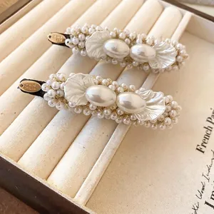 Elegant handmade pearl hair clips set with gold metal tag on a jewelry display tray
