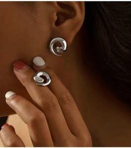 Macro shot of silver spiral twist earrings with inlaid diamond on model's ear