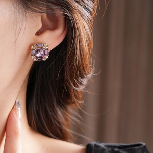 Detailed view of square purple gemstone earrings with diamond accents on model ear