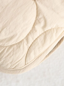 Detailed macro shot of off-white quilted jacket fabric with gourd stitch pattern