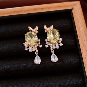 Detailed macro of 18k gold butterfly earring with yellow zircon and pearls on velvet
