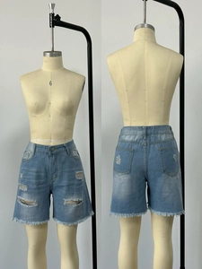 Dettaglio di pantaloncini di jeans lavati azzurri con strappi ed effetto orlo sfilacciato