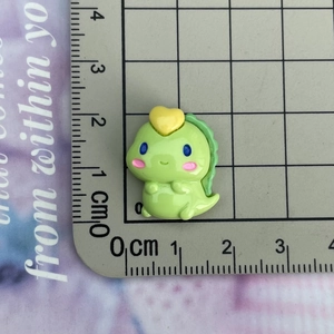 Macro scale shot showing a 2.3cm light green resin dinosaur charm with yellow heart detail