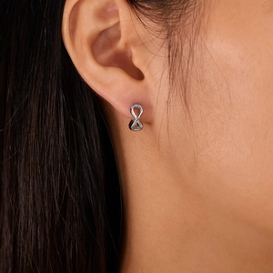 Close-up of infinity symbol stud earring in silver finish on a female model ear