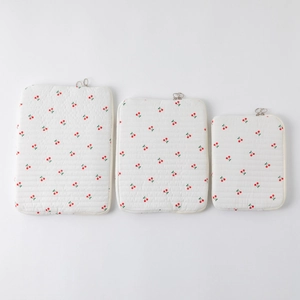 Three sizes of cream quilted tablet sleeves with red cherry print and silver zippers