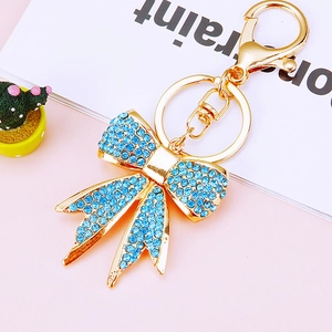 Detailed macro view of a gold metal keychain with a sparkling blue rhinestone bow charm