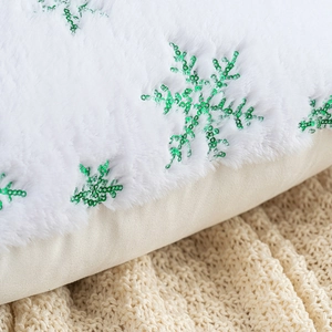 Detail of plush white pillow cover with sparkling green sequin snowflake embroidery