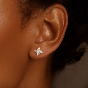 Detailed close-up of a silver S925 star-shaped earring with opal and zircon on an ear