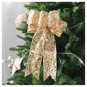 Close-up of a sparkling gold sequin bow hanging on a green Christmas tree branch
