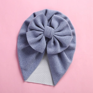 Close-up of baby beanie with a large oversized bow on a soft pink background