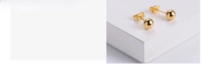 Close-up of polished gold-plated ball stud earrings with classic butterfly backings