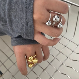 Detail showing gold three-ball and silver double-bead open rings on hand