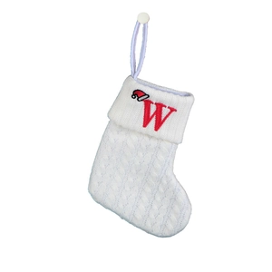 Detail of white cable knit Christmas stocking with red embroidered letter W and Santa hat