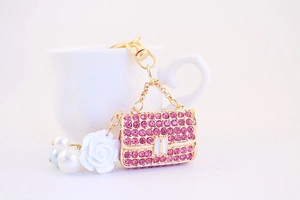 Detailed close-up of pink rhinestone handbag keychain with white camellia and pearl charms