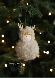 Macro detail of plush angel doll with deer antlers on a festive Christmas tree background