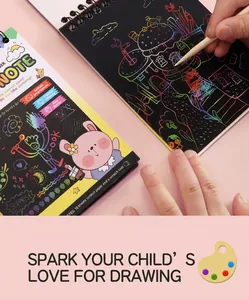 Close-up of a child drawing on a rainbow scratch art notebook with a wooden stylus pen