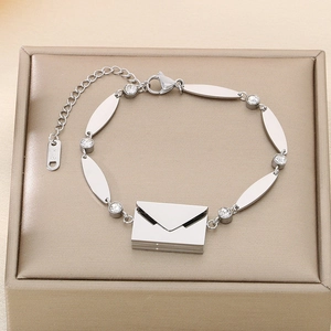 Detail view of silver envelope bracelet with zircons and K18 tag on a jewelry box