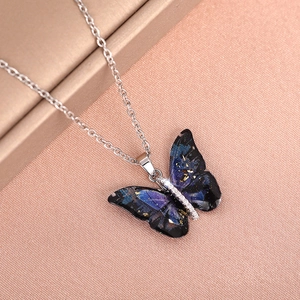 Macro shot of silver butterfly necklace with starry blue resin and sparkling stones