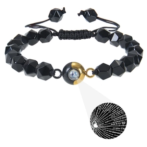 Detailed view of woven bracelet featuring black faceted beads and dual-tone projection stone