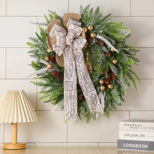 Christmas pine cone wreath with green needles, golden bells, and Merry Christmas ribbon