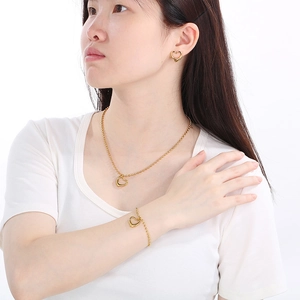 Parure dorée trois pièces avec pendentifs cœurs évidés incluant collier bracelet et boucles
