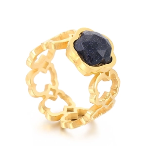 Golden hollow clover ring with faceted blue sandstone gemstone on white background