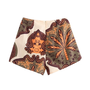 Detailed flat lay of beige printed shorts with tropical palm trees and tribal patterns