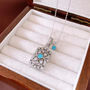 Luxurious turquoise flower pendant necklace in silver setting displayed on a wooden jewelry box