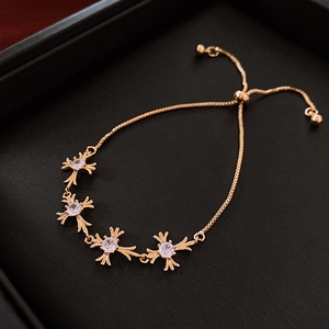 Close-up of golden zircon cross bracelet featuring adjustable drawstring on black jewelry box