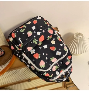 Detailed top view of black backpack featuring vibrant strawberry print on woven texture