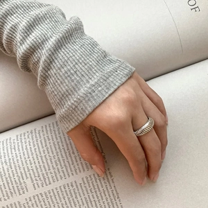 Detail of 925 sterling silver textured ring worn elegantly on hand over a book