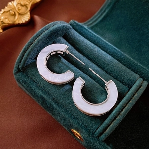 Close-up of C-shaped earrings with white faux mother-of-pearl in silver metal base