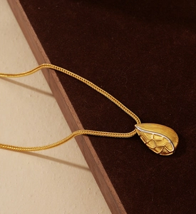 Macro shot of gold-plated teardrop pendant with brushed texture on S925 silver necklace