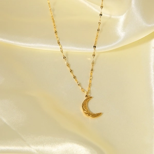 Golden irregular crescent moon pendant necklace with flat link chain on silk fabric