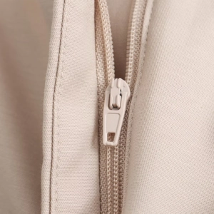 Macro shot of high-quality beige zipper detail on pleated high-waisted shorts fabric