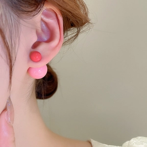 Close-up of double-sided stud earrings with red and pink round beads on female model