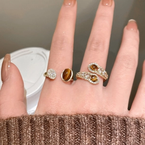 Detail of 18K gold plated tiger eye and zircon rings worn on fingers with a cozy sweater
