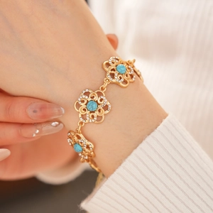 Close-up of gold flower bracelet featuring blue gemstones and crystal accents on wrist