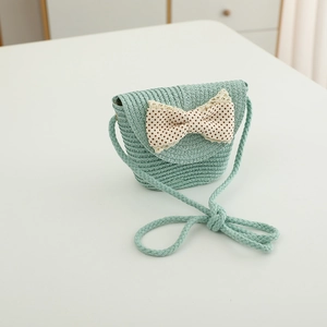 Detail of mint green straw bag with large beige polka dot bow and lace trim