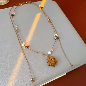 Détail macro du pendentif étoile en œil de tigre sur un collier bohème marron chic