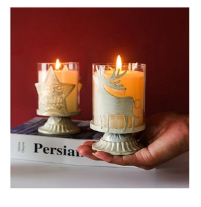 Close-up of vintage glass candles with metal deer and star bases in a cozy setting